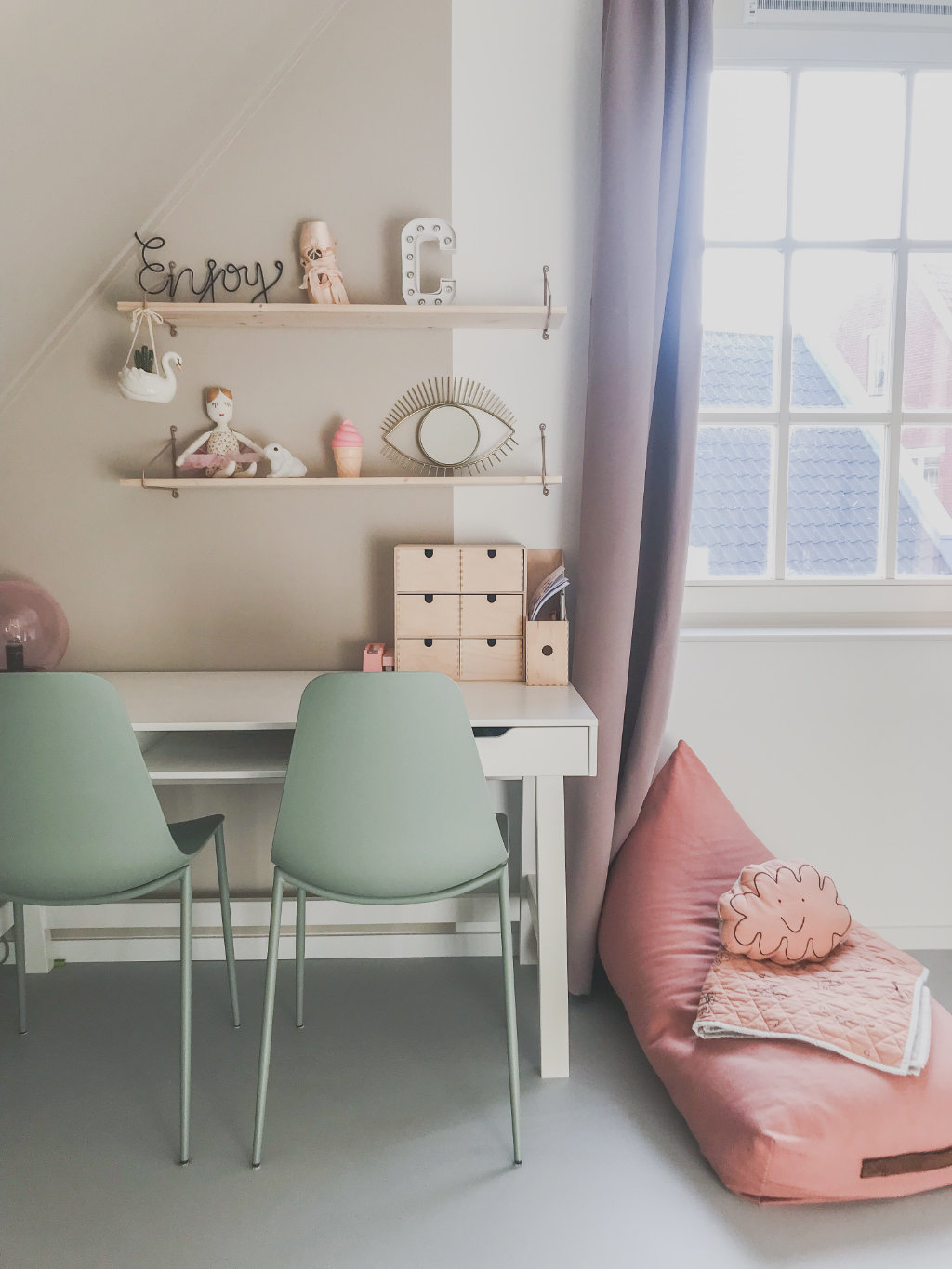 speelhoek of werkplek met groene eetkamerstoelen en roze zitzak