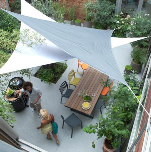 terras met houten tuintafel en gekleurde metalen tuinstoelen schaduwdoek