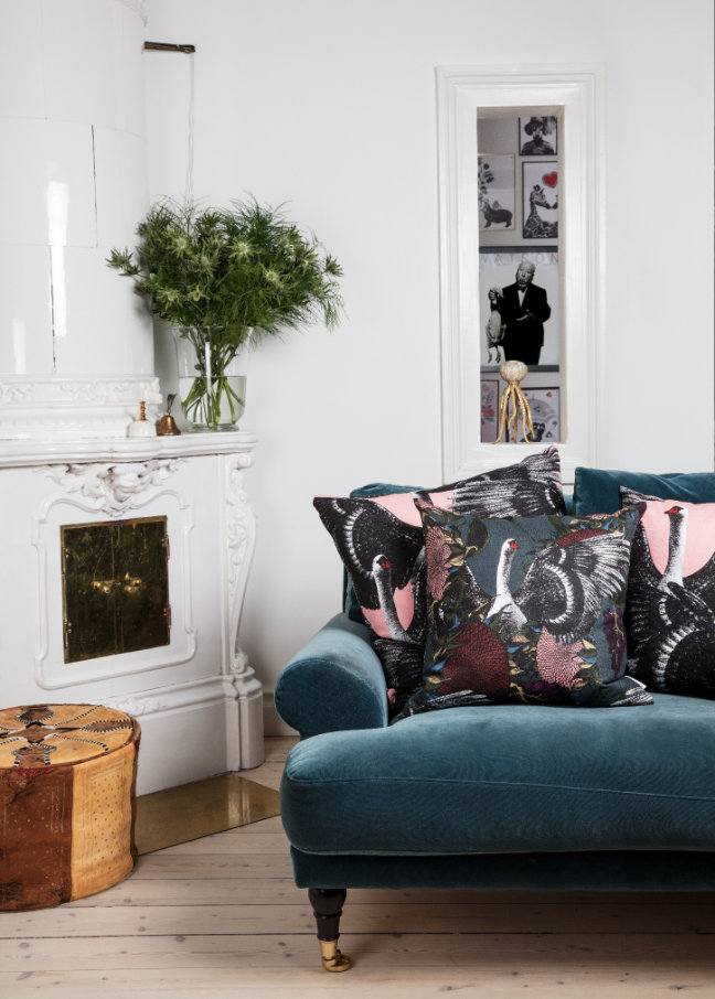 woonkamer met turquoise velours bank en kussens met zwanenprint