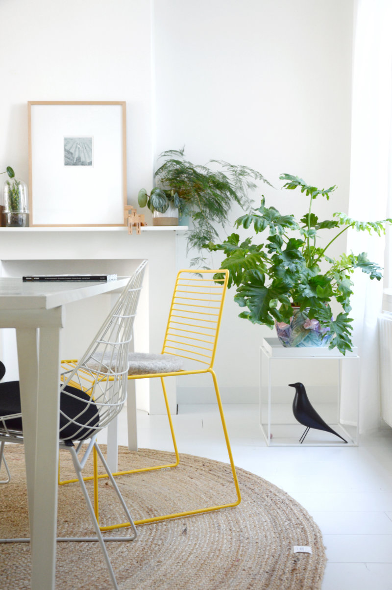 Witte eettafel met gele metalen draadstoel jute ronde vloerkleed en wit bijzettafeltje