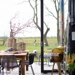 houten eettafel met zwarte rotan eetkamerstoelen die je zowel binnen als buiten kunt gebruiken