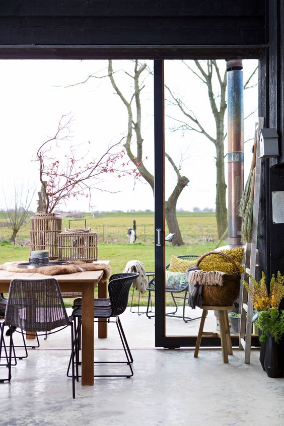 houten eettafel met zwarte rotan eetkamerstoelen die je zowel binnen als buiten kunt gebruiken