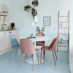 ronde eettafel in de keuken met roze en blauwe eetkamerstoelen