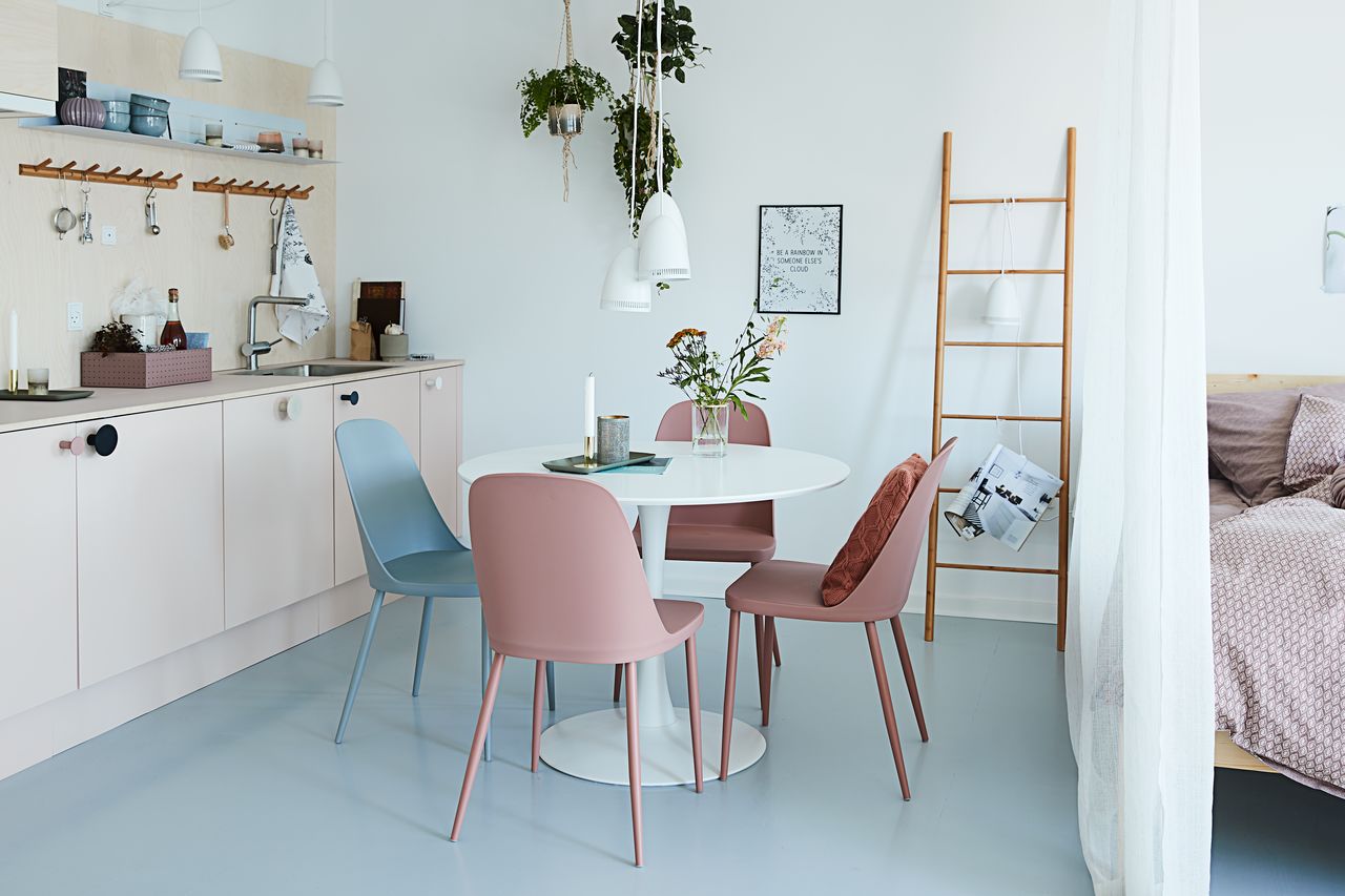 ronde eettafel in de keuken met roze en blauwe eetkamerstoelen