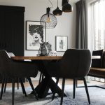 ronde eettafel met zwart eetkamerstoelen en eetkamerbank en grote zwarte houten kast