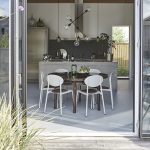 groot terras met openslaande deuren en een ronde tafel met witte stoelen