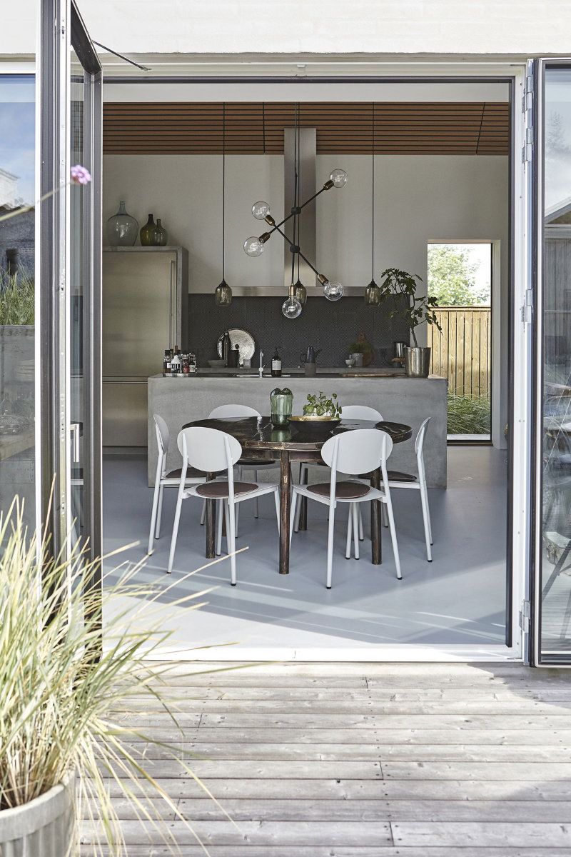 groot terras met openslaande deuren en een ronde tafel met witte stoelen