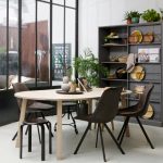 ovale houten eettafel van woood met donkere eetkamerstoelen en grijze kast swing