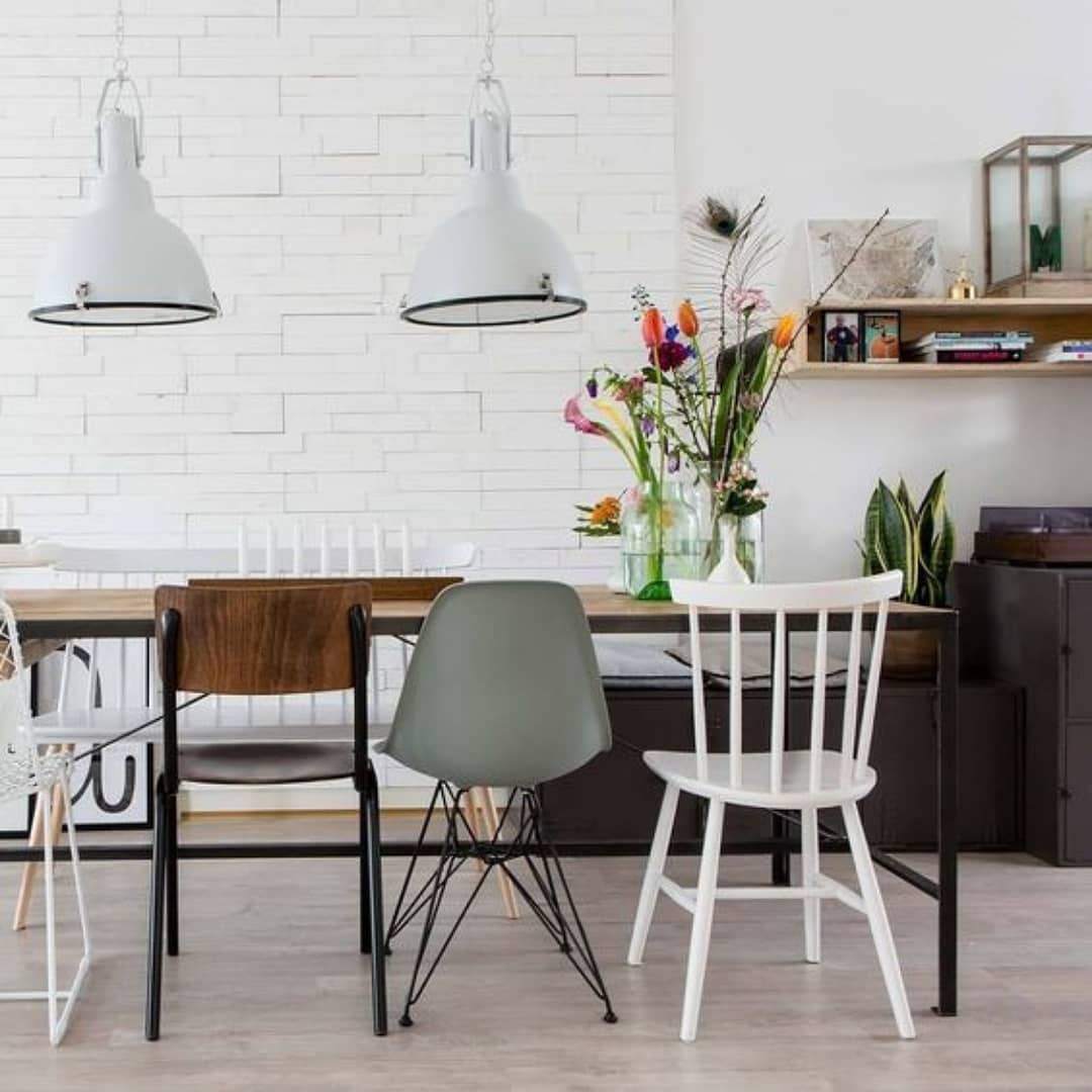 stoere industriele eettafel met verschillende eetkamerstoelen en industriele lampen