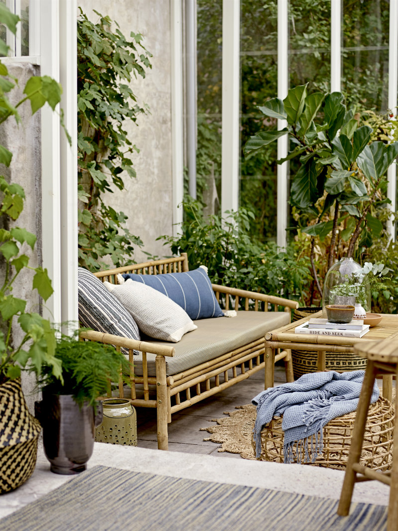 rotan tuinbank van bloomingville met blauwe kussen en salontafel van rotan