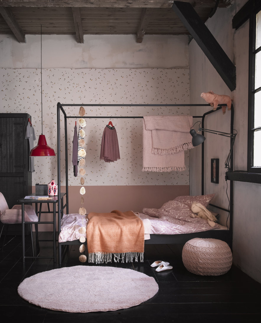 zwart hemelbed in roze meisjeskamer met roze vloerkleed plaids en poef