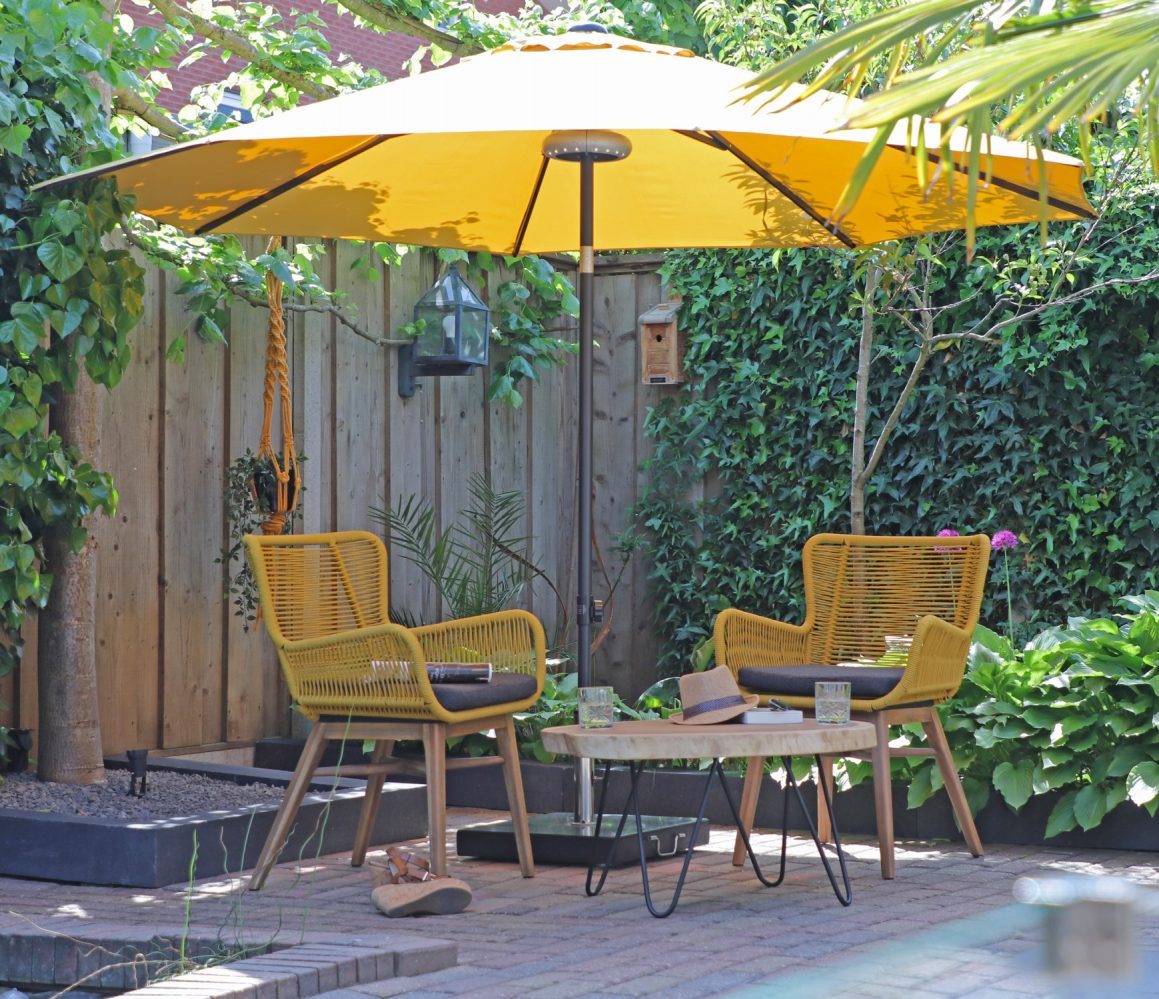 tuin met gele fauteuil tuinstoelen en gele parasol