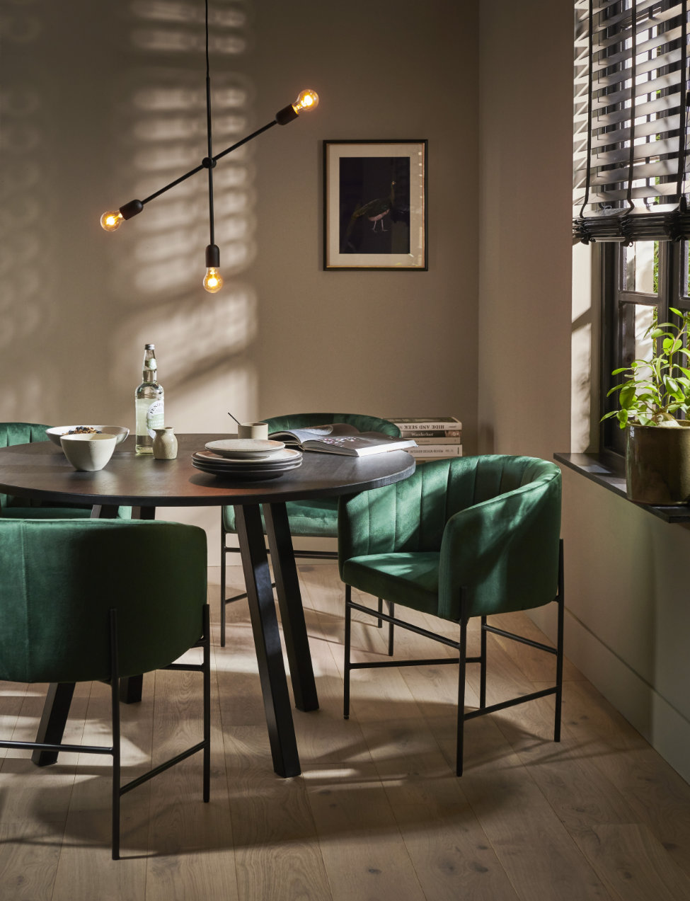 ronde eettafel met groene velours stoelen en moderne kroonluchter