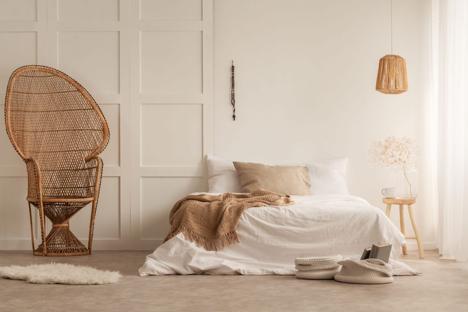 Stylish peacock chair in elegant bedroom created with natural materials, real photo with copy space on the empty wall