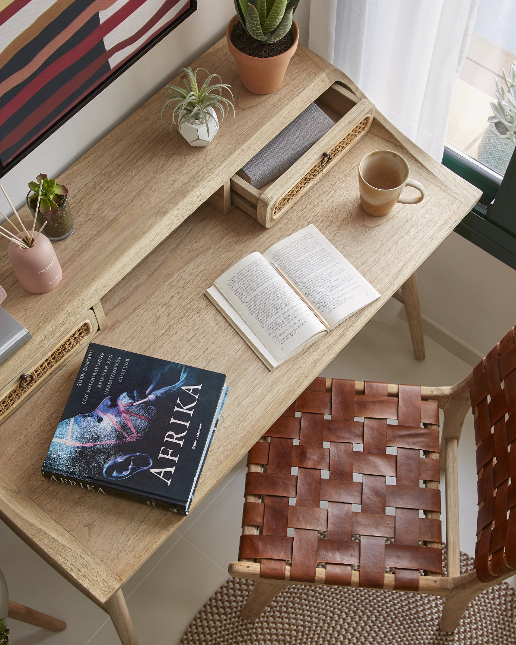 thuiswerkplek met houten bureau en stoel met gevlochten leren zitting